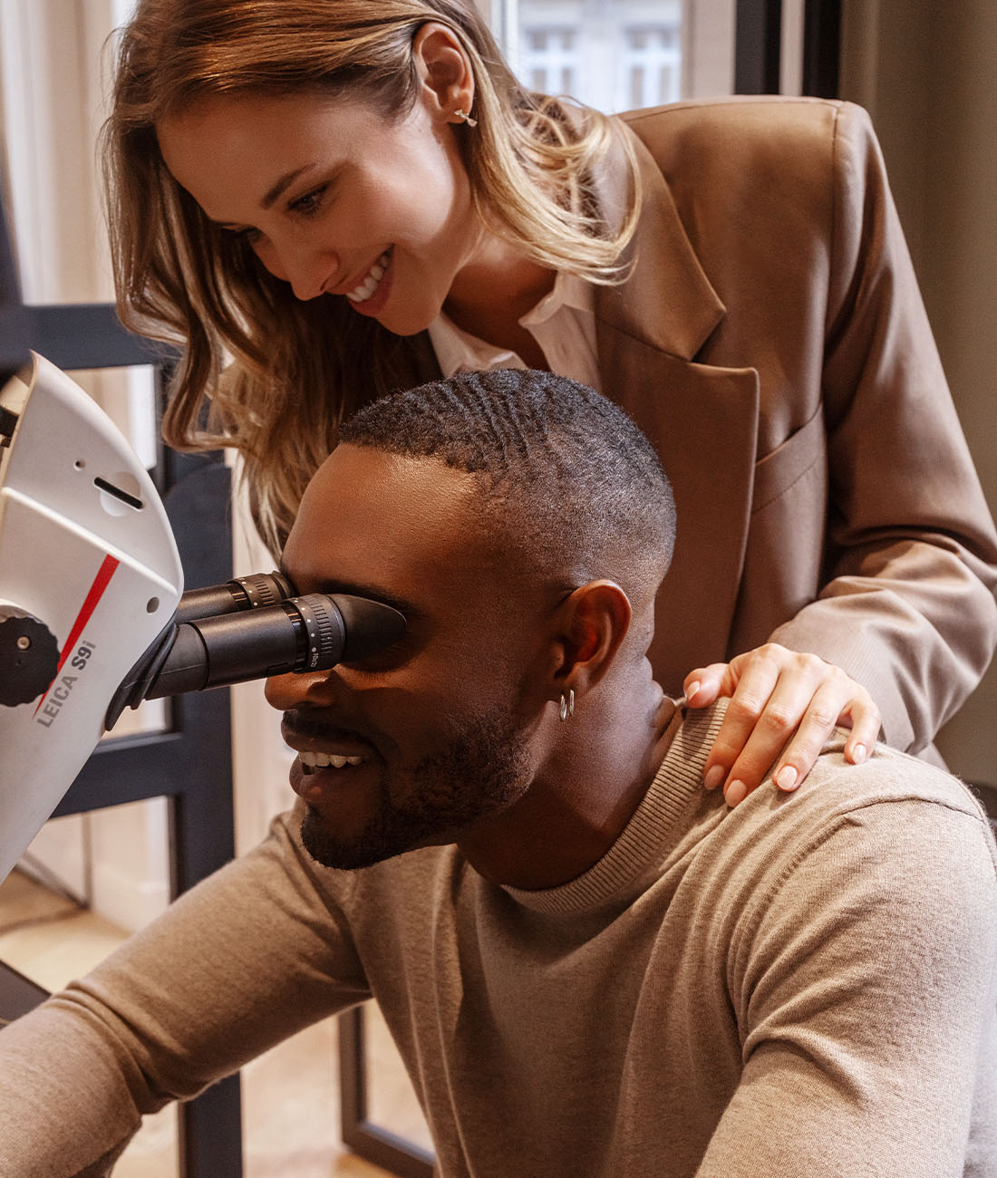 amantys_atelier_binoculaire_1_desktop Couple assis devant une binoculaire de joaillier au coeur de l'Atelier de joaillerie de la Maison Amantys